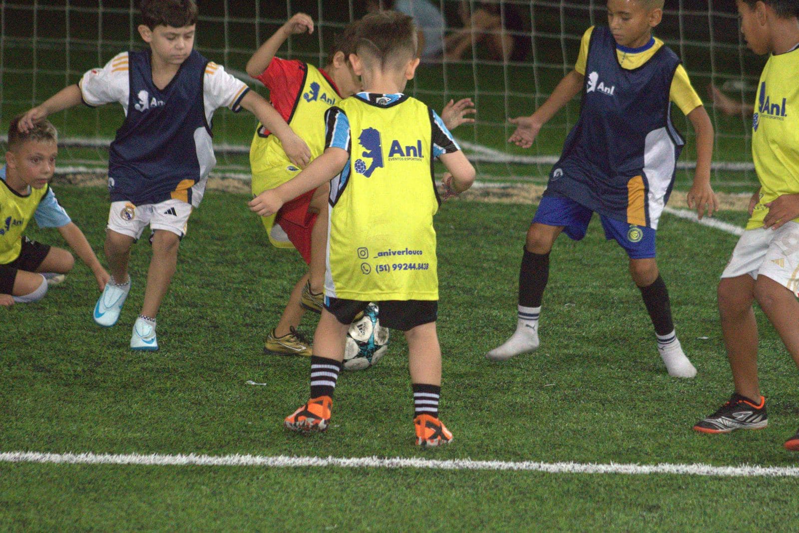 Disputa de bola entre crianças de colete do Aniverlouco